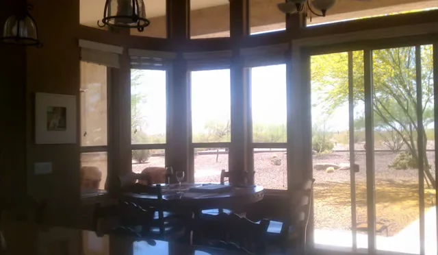 A dining room with a curved wall of windows looking out on a desert yard