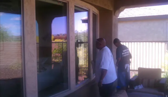 Two window cleaners working on a sliding glass door on a back patio