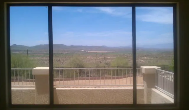 Looking through a clean sliding window at desert hills and blue sky