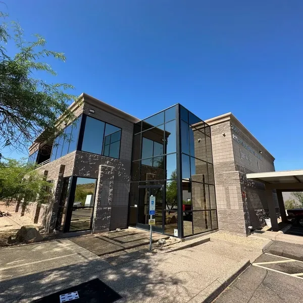 A two-story office building with dark glass walls under a clear blue sky