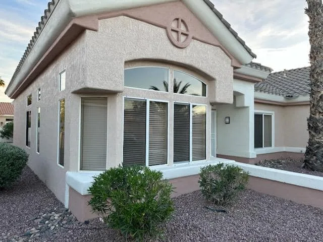 A stucco home with a bay window and an arched window above it